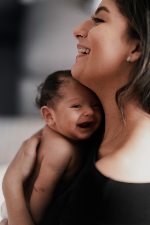 Woman holding baby smiling. Photo by Raul Angel on Unsplash https://unsplash.com/photos/woman-carrying-smiling-baby-mcKqoZh0DkI?utm_source=unsplash&utm_medium=referral&utm_content=creditShareLink